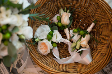 Light pink wedding boutonnieres composed of roses and freesia in the basket.