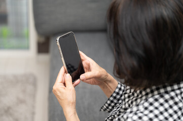 スマホを触ろうとする高齢者日本人シニア(高齢女性)  コピースペースあり
