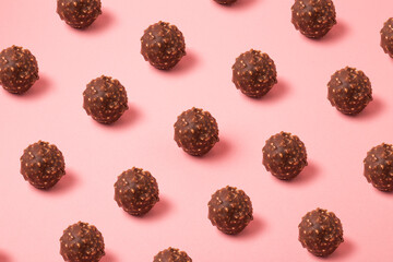 Hazelnut chocolate balls pattern on pink background, chocolate pralines backdrop