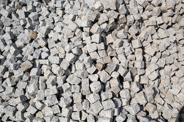 Close up of a pile of loose paving stones before being set into a cobblestone road.