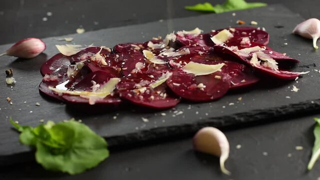 Man pours olive oil on beetroot carpaccio. Vegan food.