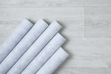 Gray textured wallpaper for walls in rolls on white wooden background.
