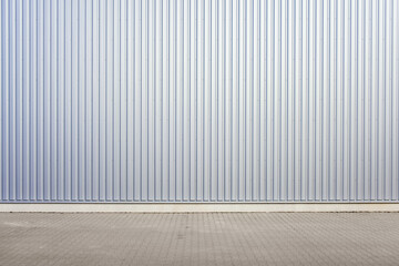Exterior wall of warehouse made of aluminum sheet and paved road in outdoor area as background...