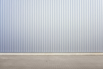 Exterior wall of warehouse made of aluminum sheet and paved road in outdoor area as background...