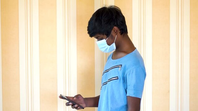 Portrait of an Indian kid wearing face mask using mobile phone