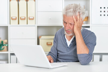 Fototapeta premium Emotional senior man using laptop