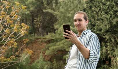 Fototapeta premium Man holding phone looking at screen watching social media video content outdoors