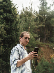 Man holding phone looking at screen watching social media video content outdoors