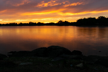 atardecer naranja sobre un lago con arboles en silueta