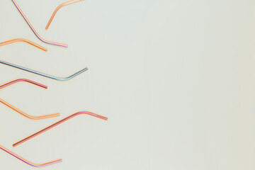 Multicolored reusable stainless steel straws on light gray background. Top view, copy space