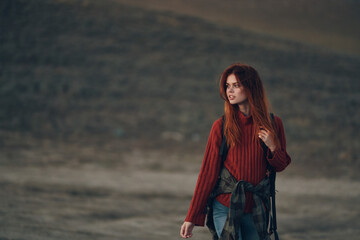 beautiful woman hiker in a red sweater walks on nature in the mountains portrait model