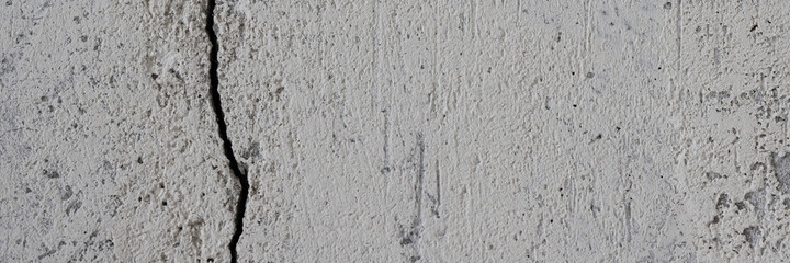 Texture of an old cracked concrete wall. Rough gray concrete surface. The gap between the reinforced concrete slabs. Wide panoramic background for design.