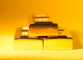 Three ingots of gold on a yellow background, the texture of gold.