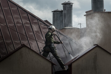 a man washing a roof with pressurized water work at a height. cleaning services protection of a...