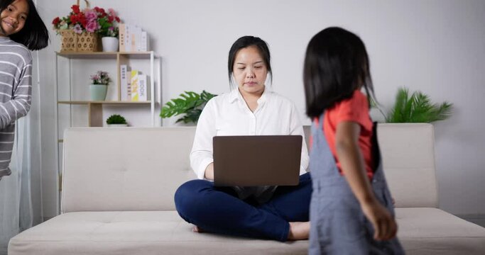 Mom concentrate on working with laptop and kids are mischievous