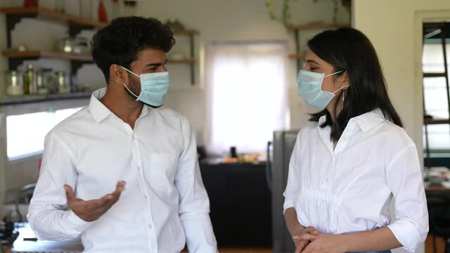 Asian Man And Woman,couple Wear Face Mask Greeting With Elbow Bump In Modern Kitchen At Home.lifestyle Concept.Employee Avoid Touch For Corona Virus Prevention.corona Virus Protection Concept.