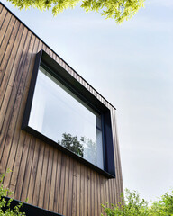 Steel window surround in a modern house with timber cladding - 435199635