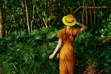 woman tourist in hat green jungle leaves exotic back view