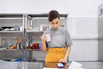 Pastry chef girl checks the Internet news feed and drinks coffee