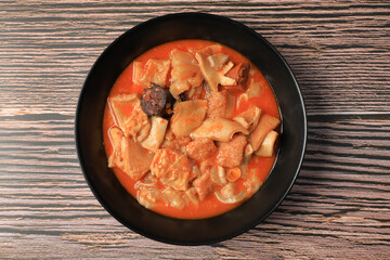 Ration of Madrid-style tripe on black plate on wooden table