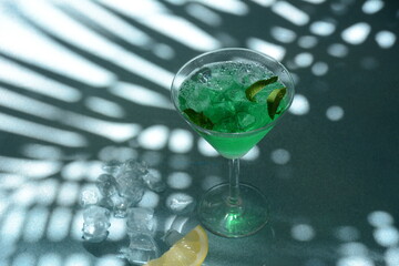 Glass of cocktail green fairy with lemon and mint leaves. Sweet refreshing mint liqueur, with ice and absinthe, rum, Ice cubes and Vodka