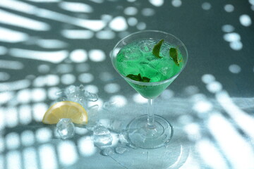 Glass of cocktail green fairy with lemon and mint leaves. Sweet refreshing mint liqueur, with ice and absinthe, rum, Ice cubes and Vodka
