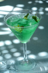 Glass of cocktail green fairy with lemon and mint leaves. Sweet refreshing mint liqueur, with ice and absinthe, rum, Ice cubes and Vodka