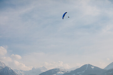 The paraglider is flying in the sky. Against the background of the mountains. Alps