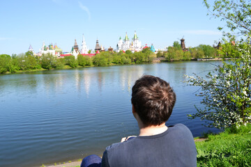 Fototapeta premium The guy sits alone on the bank of the river and looks into the distance, at the Kremlin