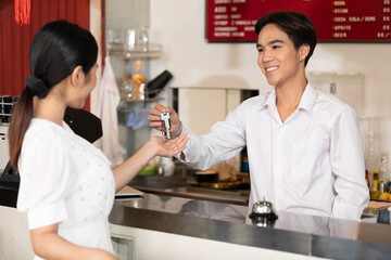 male receptionist or hotel front desk smiling and giving keycard to a customer