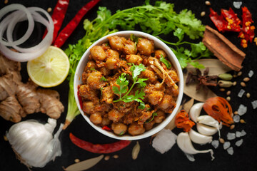 Chickpeas masala (Spicy chola or chhole curry)  garnished with fresh green coriander and ingredients. Served in a ceramic bowl. An Classic Indian typical Panjabi street food.  
