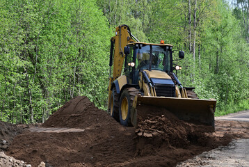 Bulldozer leveling sand piles on a country road © Dmitry