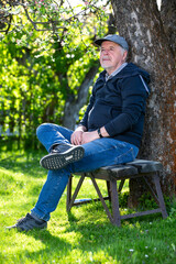 Obraz premium Portrait of a senior man outdoors, sitting on a bench in a park, optimism, good health, expression, retirement or pension concept