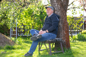 Portrait of a senior man outdoors, sitting on a bench in a park, optimism, good health, expression, retirement or pension concept