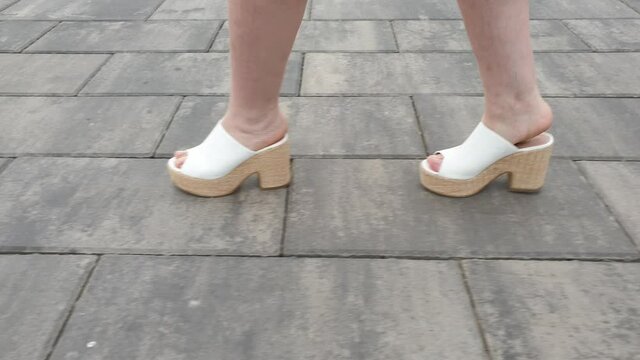 women's feet in high-heeled sandals on the sidewalk