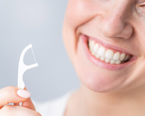 Close-up portrait of a beautiful caucasian woman with a flawless smile holding a toothpick with...