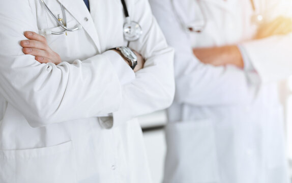 Group of modern doctors standing as a team with arms crossed in hospital office, close-up. Medical help, insurance in health care, best treatment and medicine concept