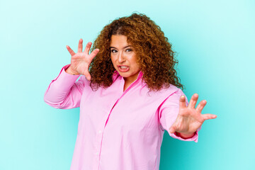 Young latin curvy woman isolated on blue background upset screaming with tense hands.