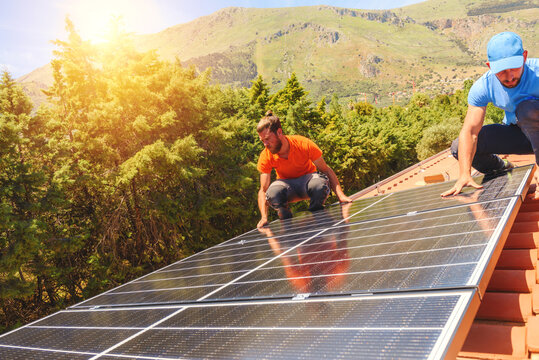 Workers assemble energy system with solar panel for electricity and hot water