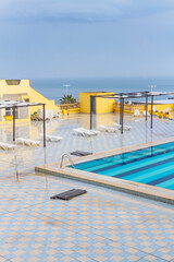 Outdoor hotel pool off season. White plastic loungers, empty pool. Resort overlooking the Mediterranean sea in off-season. Tunisia