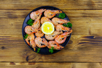 Red boiled prawns with lemon and parsley on wooden table. Top view