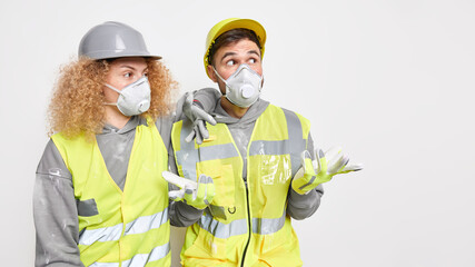 Horizontal shot of of two construction workers wear helmet protective masks and uniform isolated...