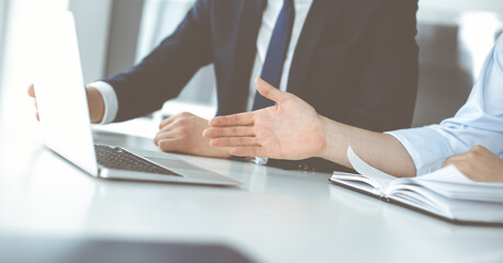 Unknown business people using laptop computer at the desk in modern office. Businessman or male entrepreneur is working with his colleague. Teamwork and partnership concept