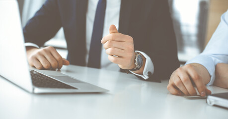 Unknown business people using laptop computer at the desk in modern office. Businessman or male entrepreneur is working with his colleague. Teamwork and partnership concept