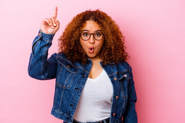 Young latin curvy woman isolated on pink background pointing upside with opened mouth.