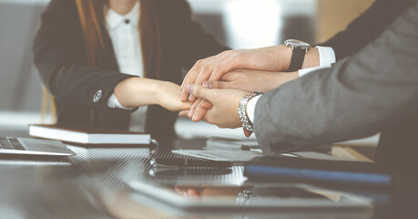 Unknown business people group joining hands in modern office. Businessmen and women making circle with their hands as a team, close-up