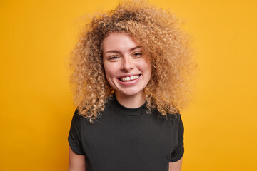 Portrait of good looking young European woman with curly bushy hair dressed in casual black t shirt...