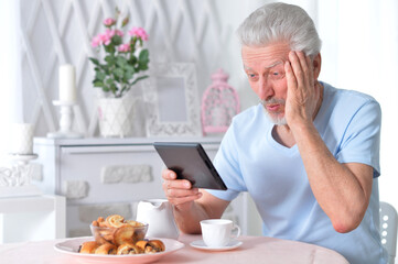senior man reading article from tablet