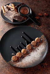 Chocolate truffles on a black plate.