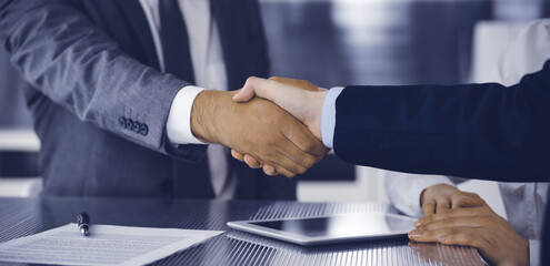 Handshake as successful negotiation ending, close-up. Unknown business people shaking hands after contract signing in modern office